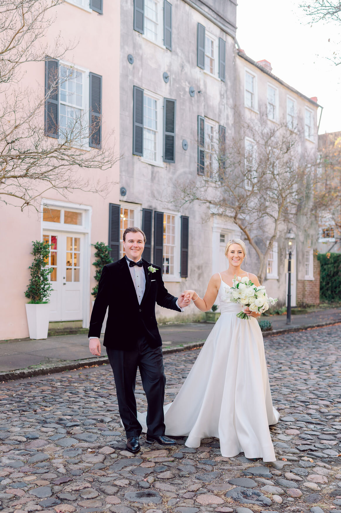 Bride and groom walking on a cobblestone street in historic Charleston SC