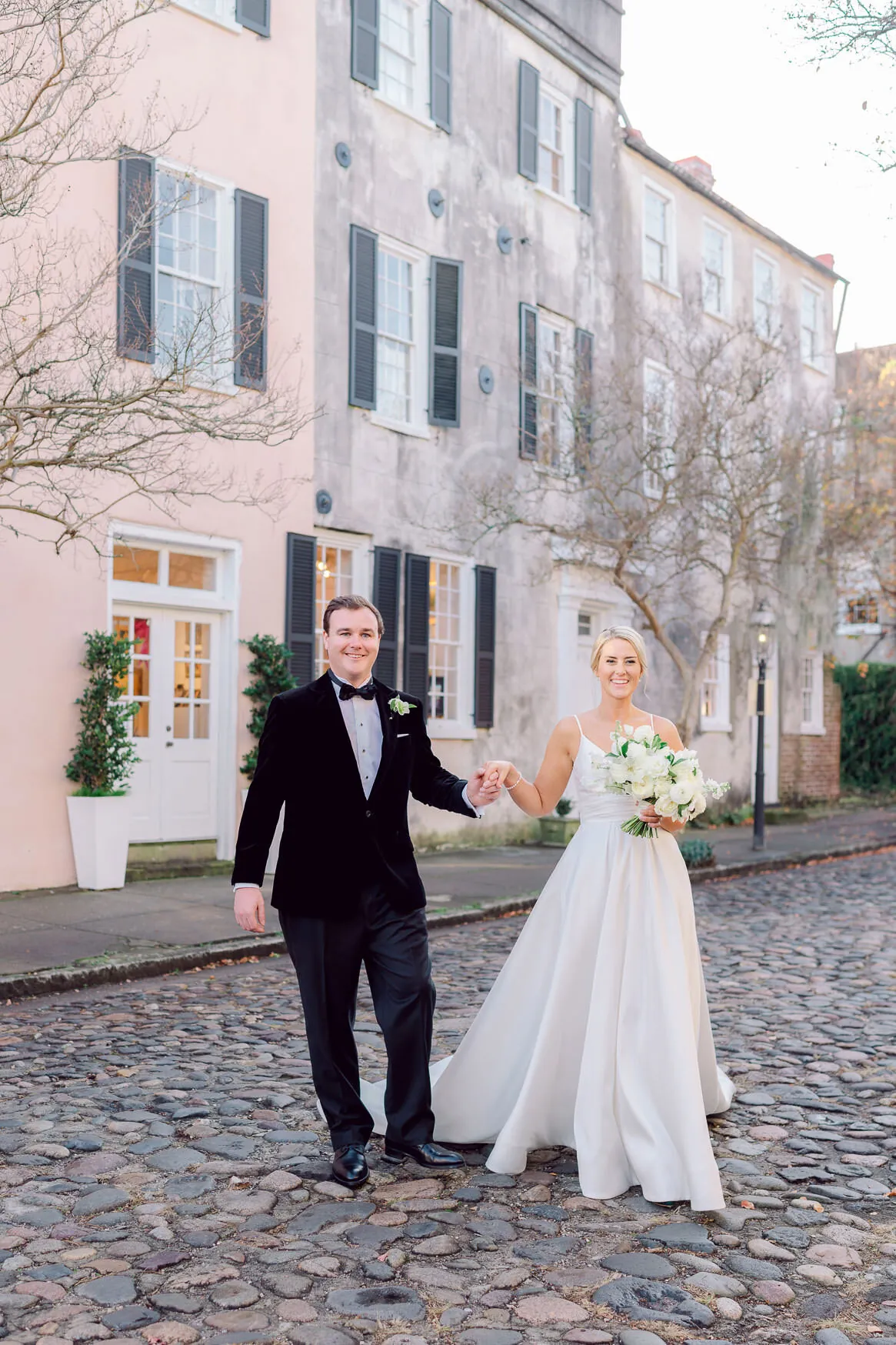 Bride and groom walking on a cobblestone street in historic Charleston SC