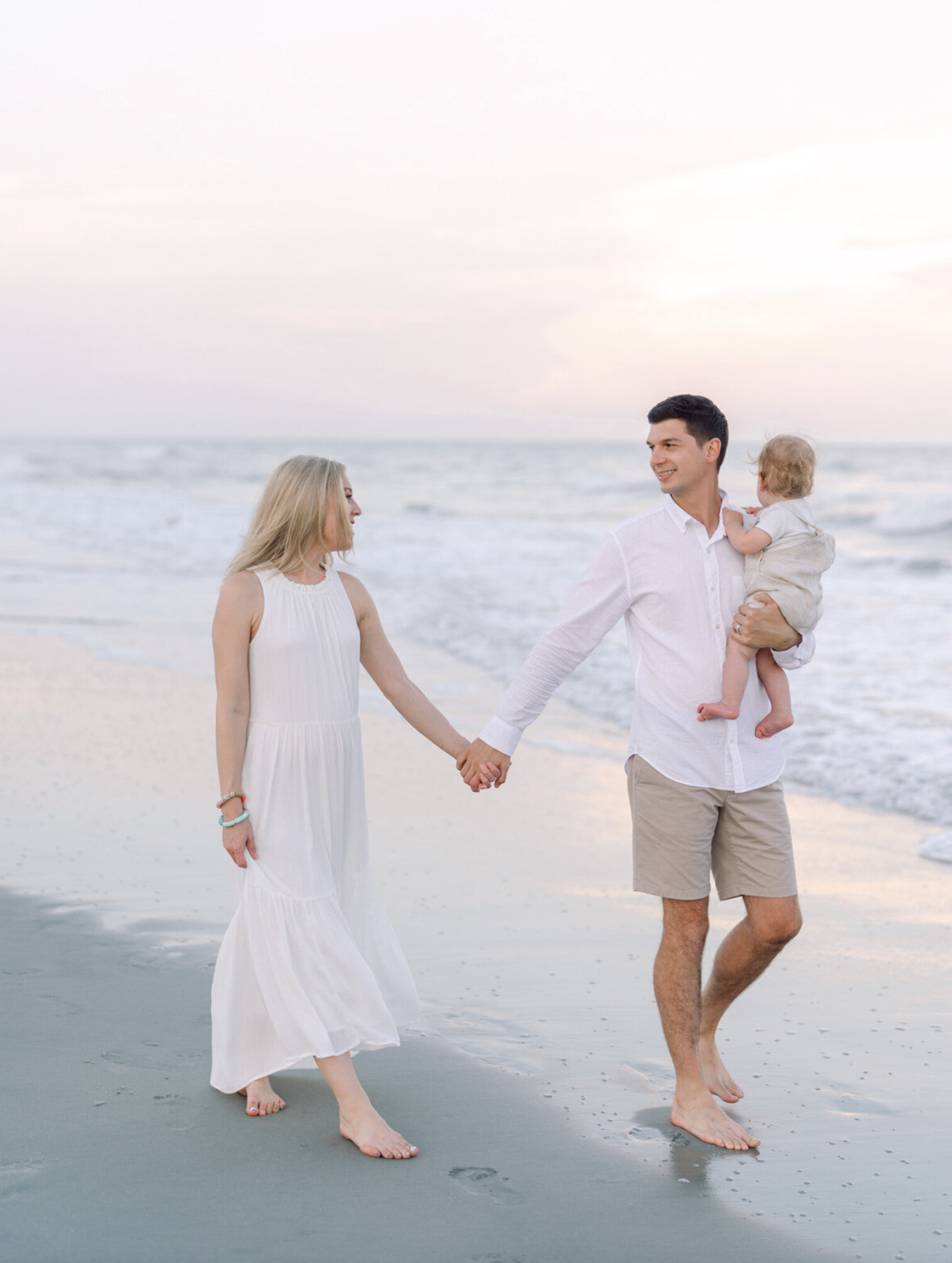 Parents walking with their young child during family photos on the beach in Myrtle Beach SC