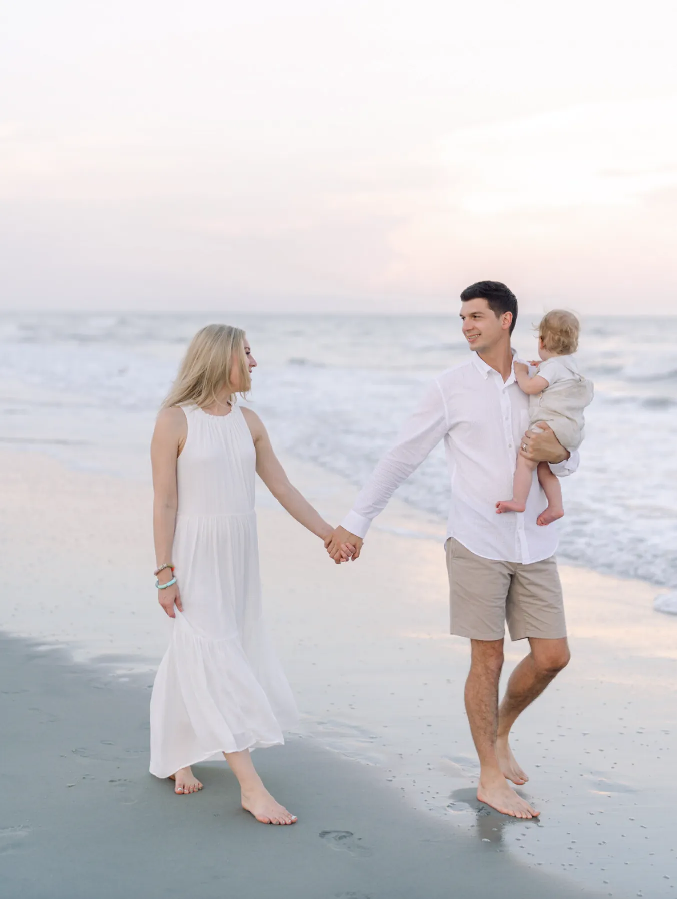 Parents walking with their young child during family photos on the beach in Myrtle Beach SC